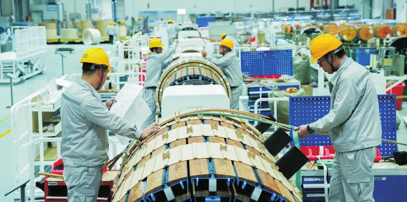 Technicians winding a power transformer coil on the large-transformer line